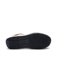 Suela de zapato con una parte inferior de goma negra con rugosidades. La sección superior beige muestra una textura suave. Contiene un logo en el centro.