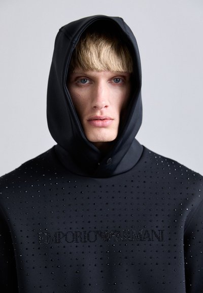 Sweatshirt preto com capuz, com uma superfície texturizada adornada com pequenos rebites e o logótipo "Emporio Armani" em detalhes de cristal.