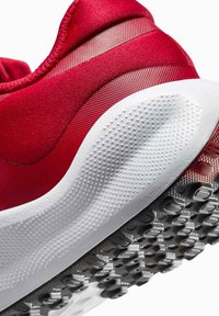 Zapatilla deportiva roja con parte superior texturizada y acentos lisos, una suela intermedia acolchada blanca y una suela exterior de goma negra con patrón.