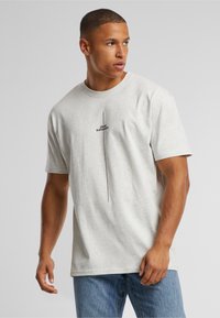 Light gray cotton t-shirt with a relaxed fit, featuring a vertical black text design "I THINK DIFFERENT." and short sleeves.