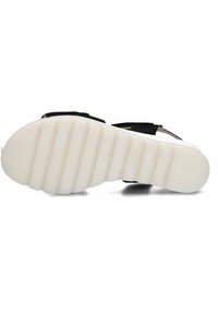 Zwarte sandaal met brede zwarte banden en een wit, gestructureerde zool met groeven voor grip. Lichtgewicht ontwerp geschikt voor casual gebruik.