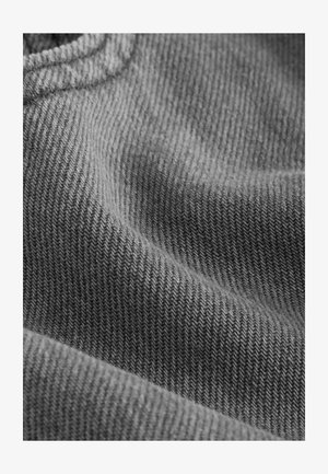 Sivo pleteno blago z ribasto strukturo, ki prikazuje subtilne diagonalne linije in mehko, rahlo puhasto površino. Zloženo, kar oblikuje nežne valove.