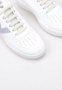 Baskets en cuir blanc avec des détails perforés, accents gris texturés, lacets plats et semelle en caoutchouc. Surface lisse et design moderne.