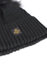Berretto oversize nero a maglia con texture a costine e un pompon rotondo in finta pelliccia sopra. Presenta una patches logo quadrato in oro e nero sul lato.