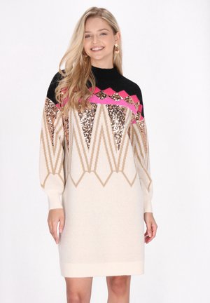 Gebreide jurk met een chevronpatroon van zwarte, roze en gouden sequins. Crème basis, lange mouwen en geribbelde manchetten. Zachte textuur, geometrisch ontwerp.