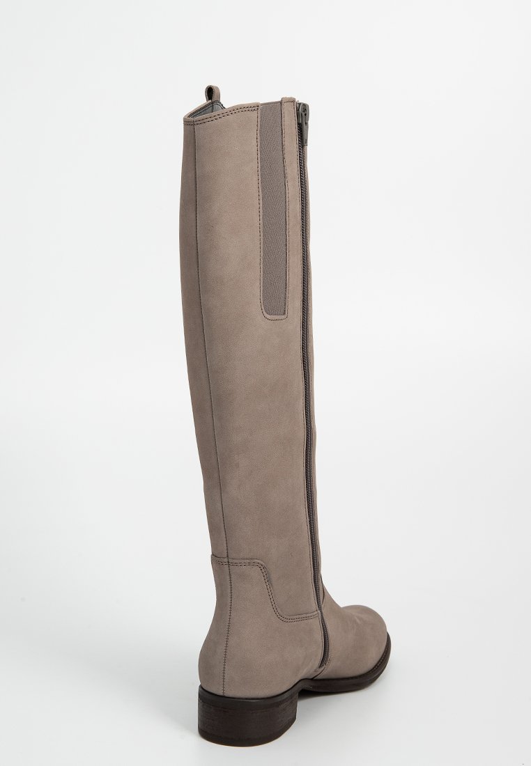 Kniehoge taupe suède laars met een gladde textuur, achterrits en een lage blokhak. Voorzien van elastische zijpanelen voor extra flexibiliteit.