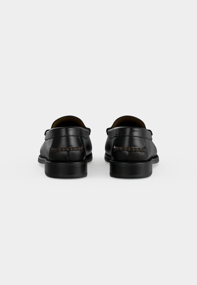 Ζευγάρι μαύρα δερμάτινα παπούτσια τύπου slip-on, εμφανιζόμενα από πίσω με χαμηλά τακούνια και ορατές λεπτομέρειες ραφής.