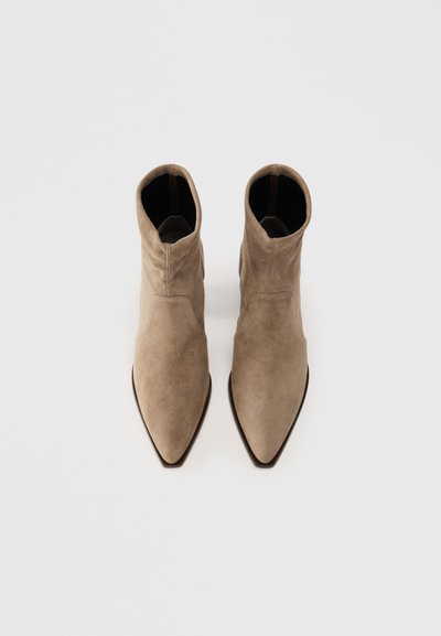 Tan suede ankle boots with a sleek, pointed toe design and a smooth texture. Features a folded collar and a black lining.
