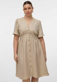 Robe beige en A avec un décolleté en V, des manches courtes bouffantes et une fermeture à boutons. Confectionnée en tissu texturé avec une taille cintrée et une jupe évasée.