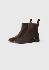Bottines en daim marron avec des panneaux élastiques sur les côtés, semelles en caoutchouc plates et languettes à l'arrière. Bout arrondi et design simple.