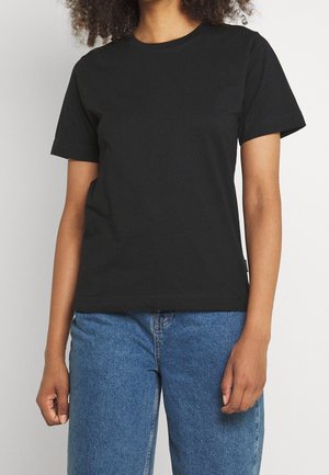 Czarna bawełniana koszulka z krótkim rękawem, okrągłym dekoltem i luźnym krojem. Połączona z niebieskimi jeansami. Prosty design, bez widocznych wzorów czy dodatków.