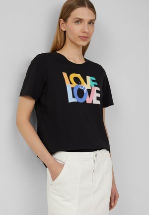 T-shirt noir à manches courtes avec un graphique multicolore qui indique "L'AMOUR est L'AMOUR". Fabriqué en coton doux. Coupe simple et décontractée.