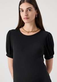 Top negru cu dungi, cu mâneci scurte tip puff, guler rotund și material texturat; asortat cu o brățară din lanț și cercei rotunzi.
