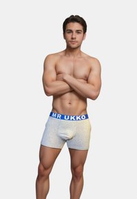 Grå bomullskalsonger med en blå midjeband som är märkt "MR UKKO." Passformen är åtsittande och har en framficka.