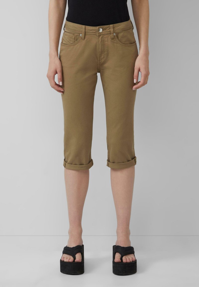 Spodnie do kolan z podwiniętymi mankietami w jasnobrązowej mieszance bawełny; pięć kieszeni, z zamkiem i zapięciem na guzik. Noszone z sandałami na platformie.