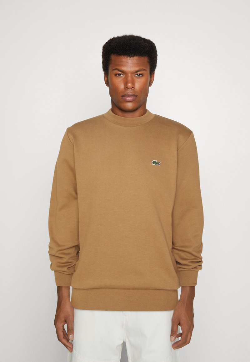 Bruine sweatshirt van katoen met een ronde hals, lange mouwen en een klein groen logo op de borst. Heeft ribgebreide manchetten en een boord.