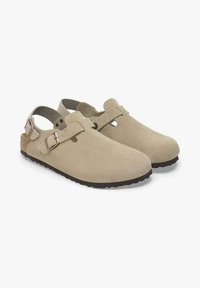 Zoccoli in suede beige con cinturino posteriore e fibbia in tonalità argento, dotati di una texture liscia e di una soletta in sughero sagomata.