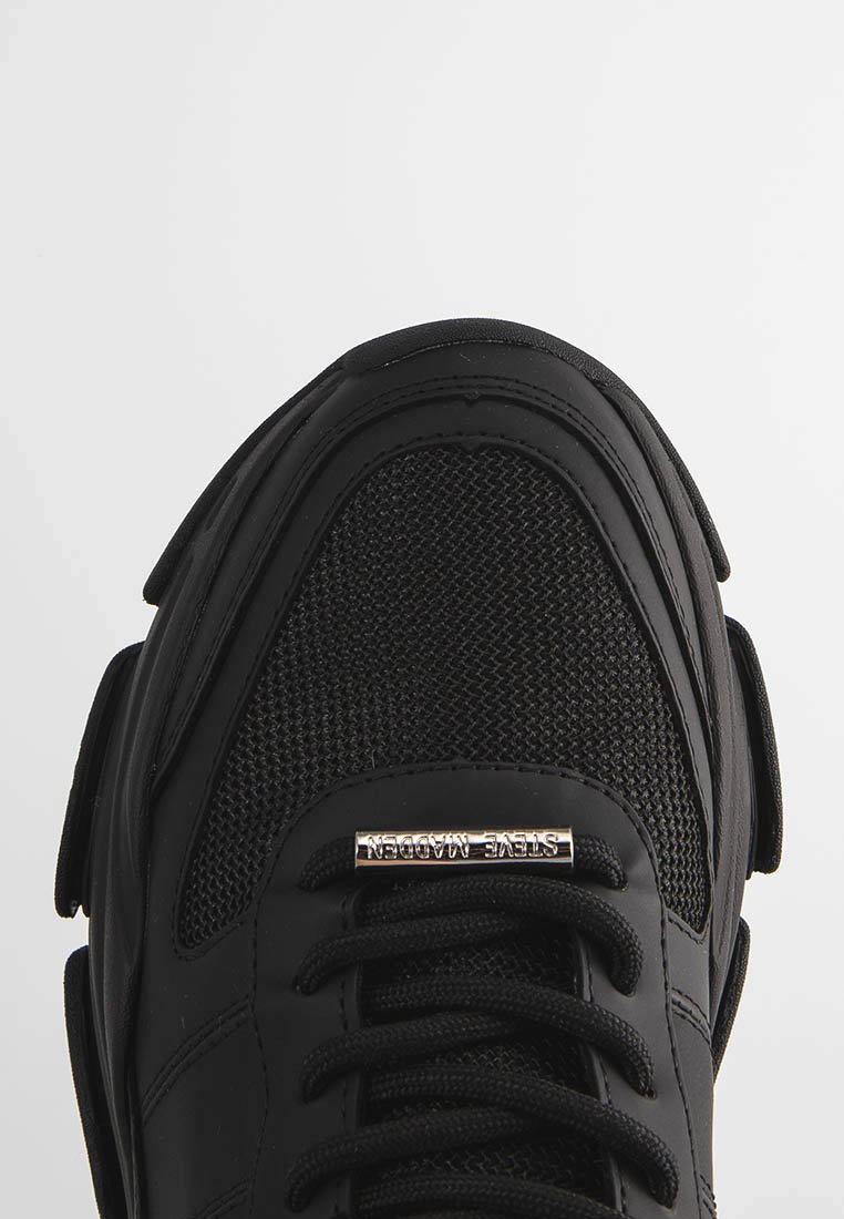 Svart sneakers med en strukturerad mesh-överkonstruktion, släta syntetiska överlägg och en metallisk logotypdetalj på tungan. Tjock, vadderad sula.