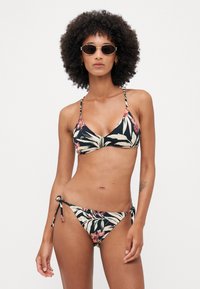 Svart bikini med blomsterdesign som har rosa og grønne blader. Trekantet topp og knytet sideslips. Glatt stoff, slanke stropper.