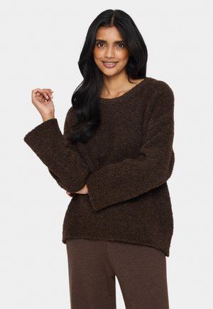 Brown fuzzy sweater with a relaxed fit, wide sleeves, and a round neckline, paired with dark brown pants. Soft texture and casual design.