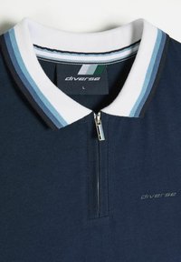 Granatowa koszulka polo z białym i niebieskim paskowanym kołnierzykiem, zamkiem na szyi oraz wytłoczonym logo "diverse" w prawym dolnym rogu. Wykonana z miękkiego materiału.