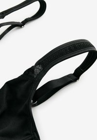 Soutien-gorge noir avec bretelles réglables. Doté d'un tissu doux, d'une accent en dentelle sur les bretelles et d'une quincaillerie en métal pour les ajustements. Design simple.