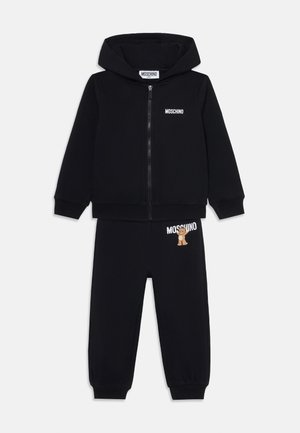 Schwarzer Moschino Trainingsanzug mit einer Zip-Hoodie und einer elastischen Taillenhose. Äußert ein Bärenmotiv auf der Hose und Logo-Text auf dem Hoodie.