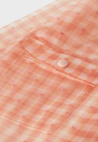 Przezroczysty różowy płaszcz przeciwdeszczowy w kratę, z małymi serduszkami, posiadający przednią kieszeń oraz zapięcie na zatrzask.