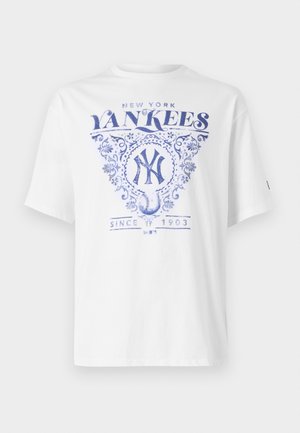 Bela majica s kratkimi rokavi in modrim natisnjenim dizajnom, ki vsebuje "New York Yankees", okrasne detajle in "Od leta 1903" pod grafiko bejzbola.