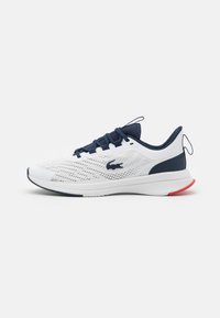 Chaussure de sport blanche avec des accents bleu marine, tige en mesh, semelle rembourrée et talon rouge contrastant. Dispose d'une fermeture à lacets et d'un détail logo.