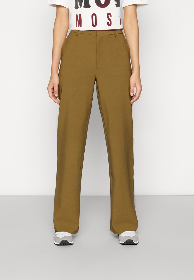 Högmidjade, vida byxor i olivgrön tyg med framveck och en slät textur. Matchas med en kortärmad grafisk t-shirt och sneakers.