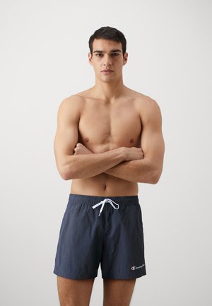 Costumi da bagno blu scuro con una texture leggera, cinturino elastico e coulisse bianca. Presenta il logo sul lato sinistro in basso.