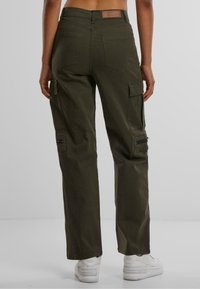 Pantaloni cargo verde oliva con una vestibilità rilassata, dotati di doppie tasche laterali, tasche posteriori e un dettaglio con zip sulla gamba destra.