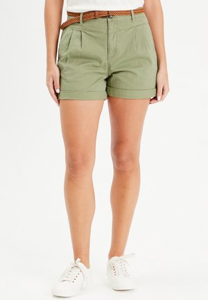 Olive green cotton shorts with a pleated design, rolled hem, and a woven brown belt. Paired with white sneakers.