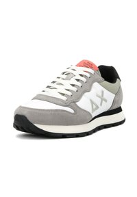 Sneaker grigio e bianco con materiali in suede e tessuto, tonalità neutre, suola texturizzata e un'etichetta rosa sul tallone con testo.
