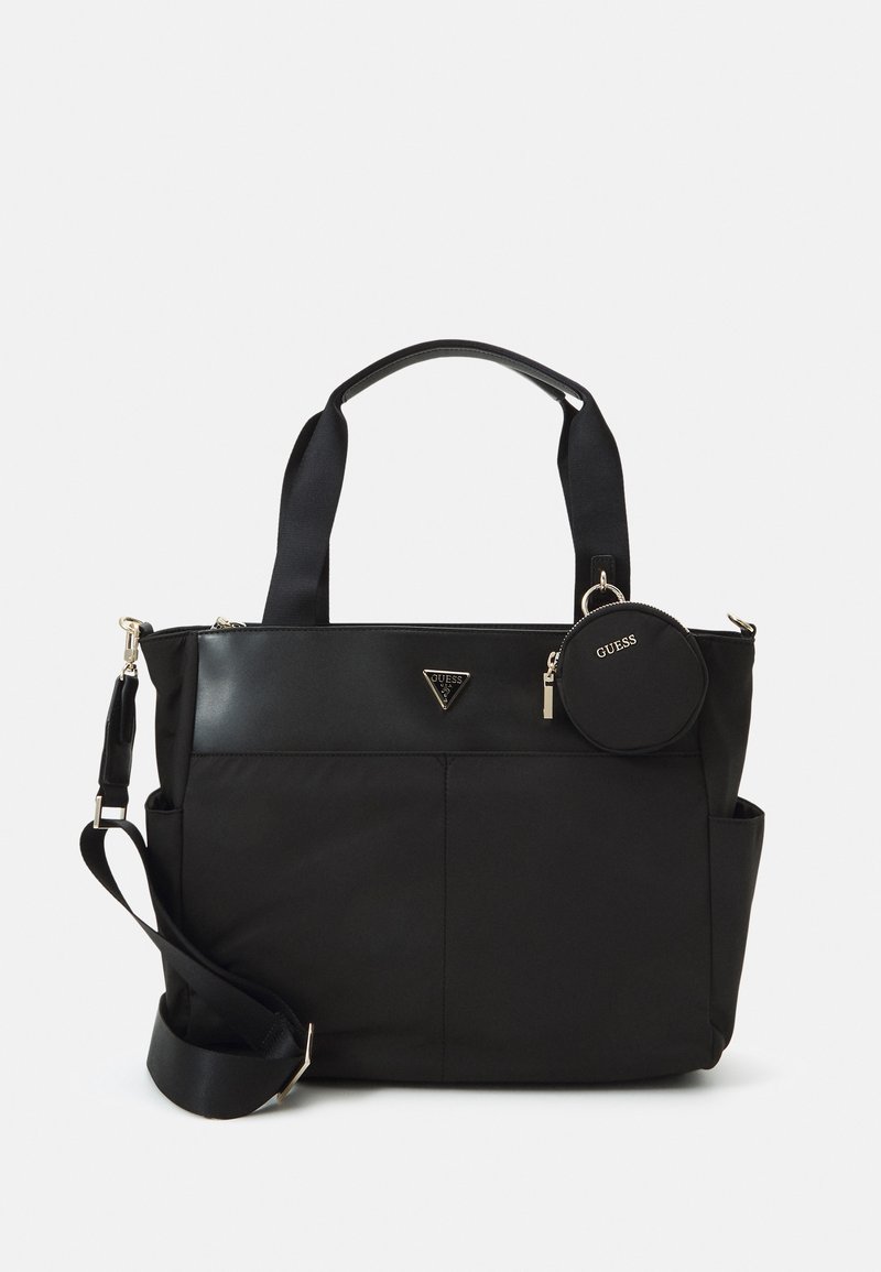 Sac cabas noir Guess avec des poignées courtes, une bandoulière réglable, des poches avant et une pochette ronde attachée à une poignée.