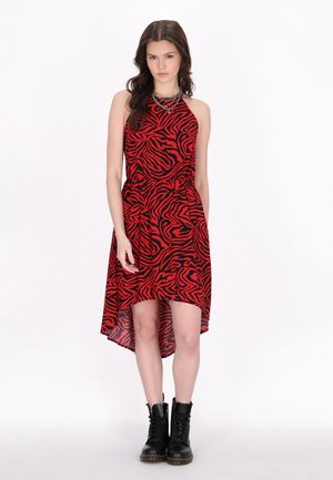 Rotes und schwarzes Kleid im Zebramuster, Halterneck-Design, hinten etwas länger, getragen mit schwarzen Schnür-Stiefeletten.