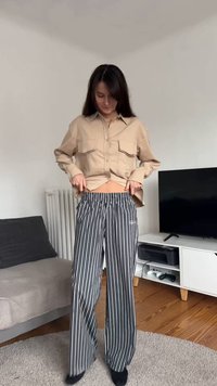 Beige skjorta med knappar och två bröstfickor, kombinerad med svartvita randiga vida byxor, elastisk midja och mjuk textur.