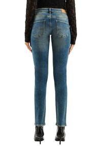 Obcisłe niebieskie dżinsy z wyblakłym wykończeniem, widocznymi tylnymi kieszeniami oraz skórzaną naszywką na tylnej części pasa. Noszone z czarnymi kozakami na wysokim obcasie.