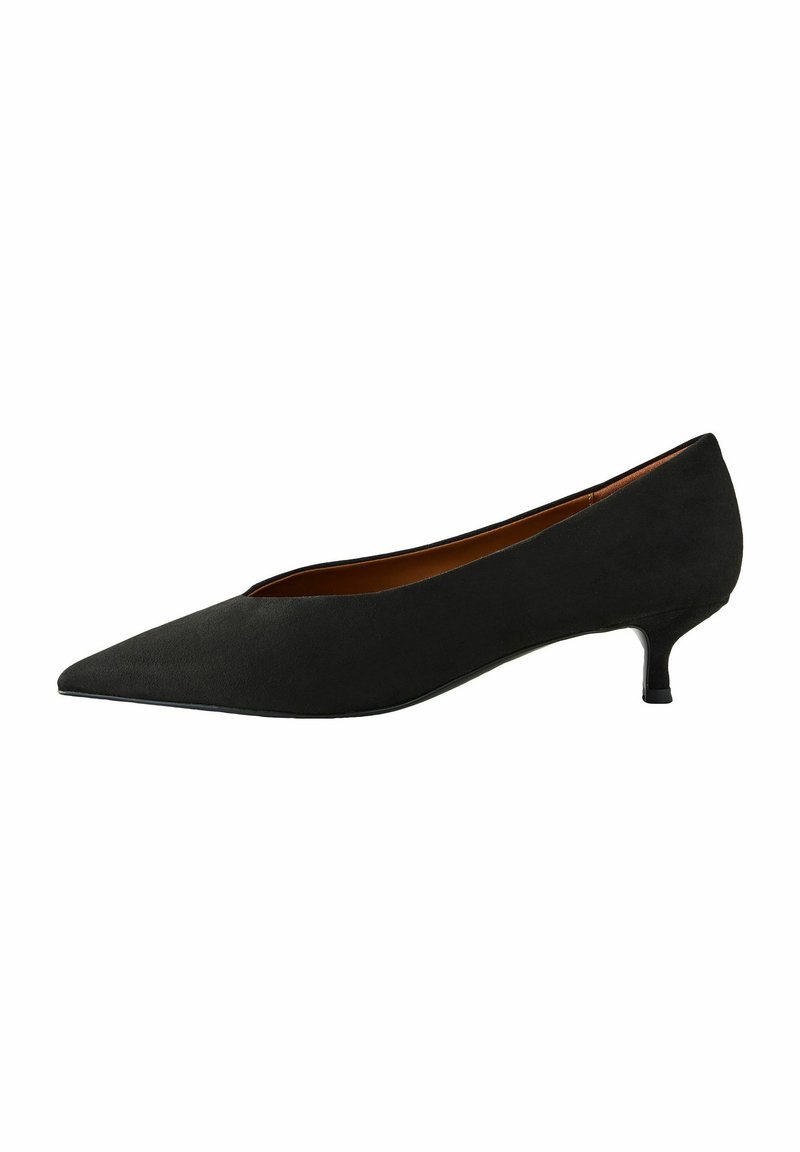 Svart mocka pumps med spetsig tå och låg kitten-häl. Slät textur, elegant design och en minimalistisk siluett. Brun inredning.