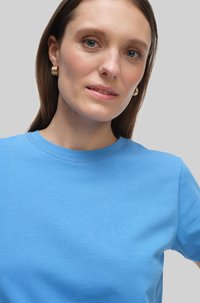 Niebieska bawełniana koszulka z okrągłym dekoltem i krótkimi rękawami, o gładkiej fakturze i bezszwowym designie.