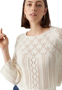 Maglione lavorato a maglia color crema con un design ad openwork a motivo diamante, maniche larghe e scollatura rotonda. Texture morbida.