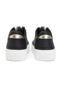 Μαύρα αθλητικά παπούτσια με υφή δερμάτινου πάνω μέρους, μεταλλική χ ρυσή λεπτομέρεια στη φτέρνα και λευκή σόλα πλατφόρμα με ανάγλυφο λογότυπο.