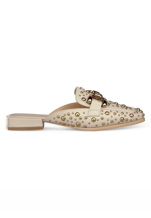 Beige Slipper mit flachem Absatz, verziert mit goldenen Nietenakzenten und einem Schnallenriemen über dem Vorderblatt. Glatte Textur, abgerundete Zehen.