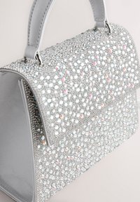 Petit sac à main structuré avec une poignée supérieure entièrement recouverte de strass argentés scintillants et une fermeture à rabat.