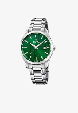 Sudraba nerūsējošā tērauda pulkstenis ar zaļu teksturētu ciparnīcu, lielu romiešu skaitli XII, sudraba rokas un datuma logu. Safīra kristāls.