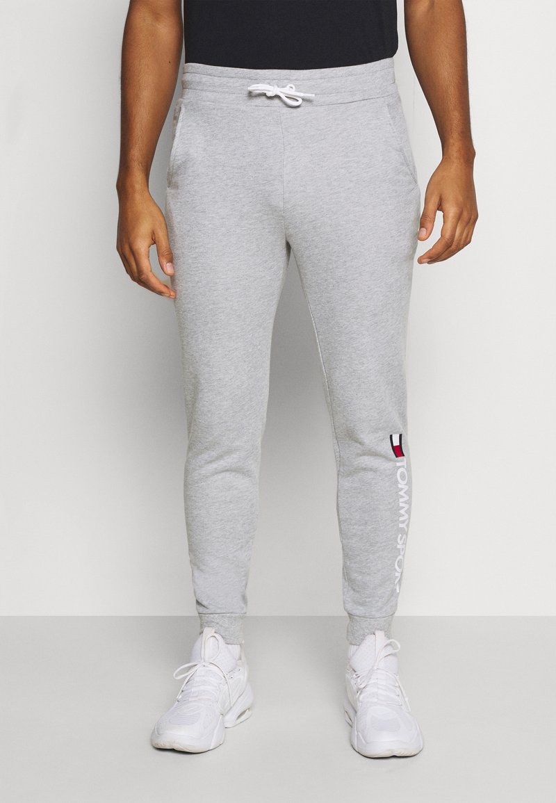 Pantalones de chándal grises de algodón con piernas ajustadas, cintura elástica con cordón, bolsillos laterales y logo "TOMMY SPORT" impreso en blanco.