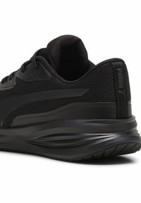 Zapatilla deportiva negra con parte superior de malla texturizada, cuello acolchado y suela de goma flexible con un diseño de ola para mayor soporte.