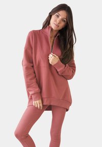 Set di felpa e leggings in rosa polveroso. La felpa presenta una zip a metà davanti, texture a coste e una vestibilità rilassata. I leggings hanno una finitura liscia.