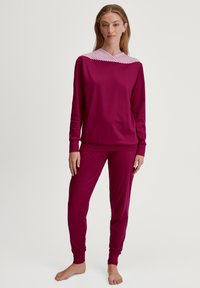 Bordeaux loungewear set bestaande uit een langmouwtop met een gestreepte schouderpartij en bijpassende tapered broek gemaakt van zachte stof.